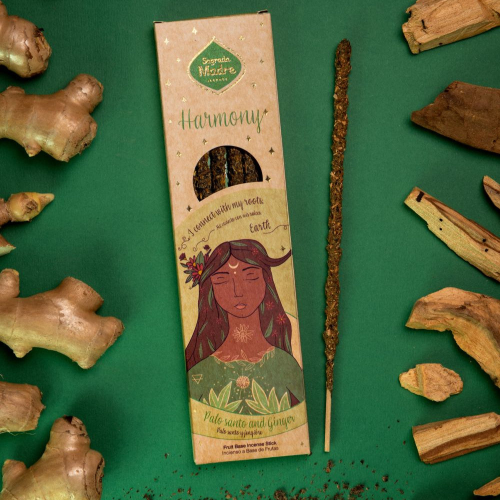 A box of incense sticks labeled 'Harmony' with an illustration of a woman, surrounded by broken pieces of Palo Santo wood and ginger on a green background.