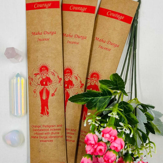 A packet of incense sticks with a printed女神MaháDüríça figure, alongside decorative flowers and leaves.