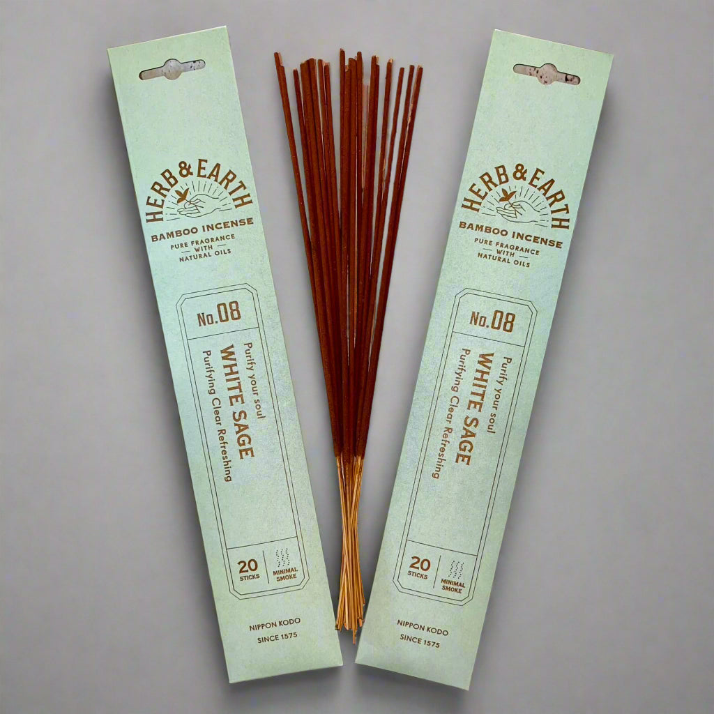 A packet of Herb & Earth bamboo incense sticks with the label showing 'WHITE SAGE' and the number '20', indicating 20 sticks are included. The incense sticks are displayed both in and out of the packaging, revealing their slender and long form.