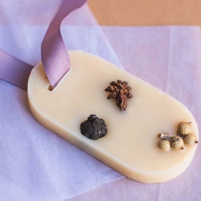 White chocolate bar with spices and a purple ribbon on a light purple background