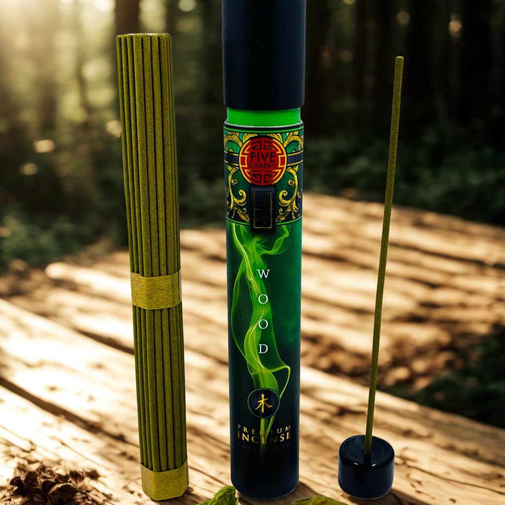 Two incense sticks in decorative holders on a wooden surface with a forest background