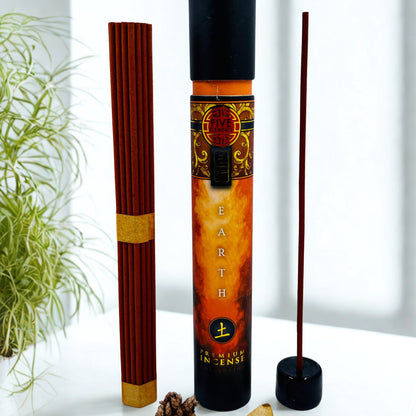 Incense stick container with incense sticks on a white surface with a plant in the background