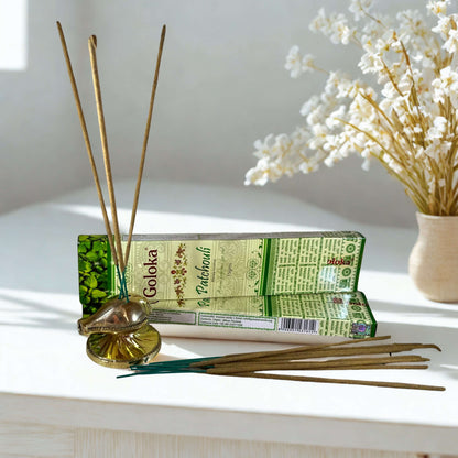 Goloka incense sticks with packaging on a white surface with a vase of flowers in the background