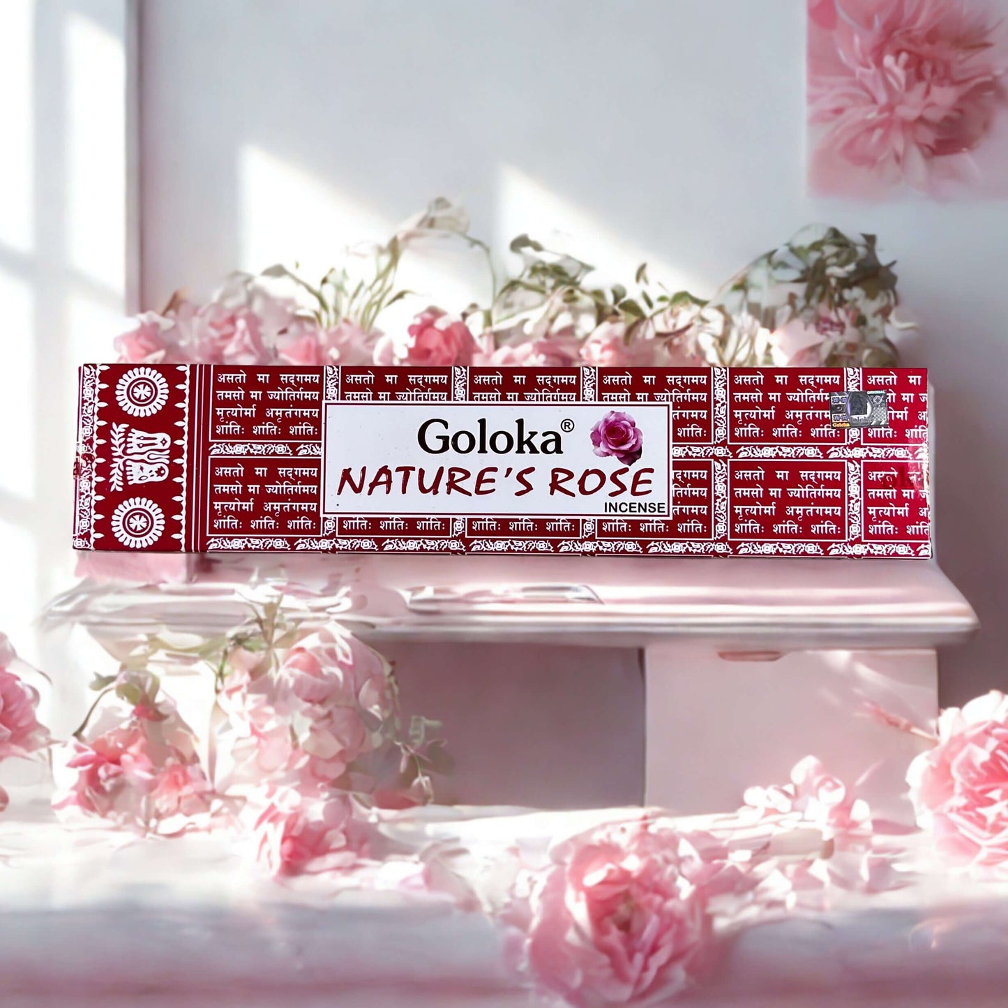 Goloka Nature's Rose incense packaging on a decorative stand with pink flowers.
