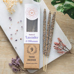 A package of Green Tree brand incense sticks labeled 'Lavender & Olibanum', with nine sticks visible in the packaging, placed on a wooden surface with decorative flowers and a crystal flower in the background.
