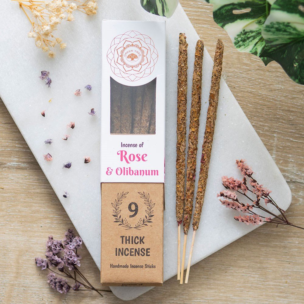A package of Green Tree Rose & Olibanum Botanical Incense Sticks, with 9 sticks visible outside the package. The packaging is brown with a white and pink floral design and the text 'Thin & Intense'.