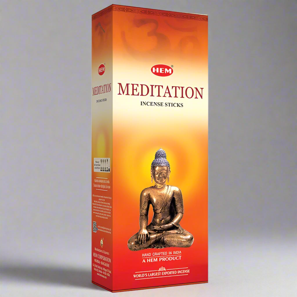 Box of HEM Meditation incense sticks with a Buddha statue on an orange background