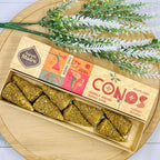 Handmade incense cones displayed in a wooden box with a label showing 'SAGRADA MADRE' and 'CONOS', accompanied by a sprig of rosemary.