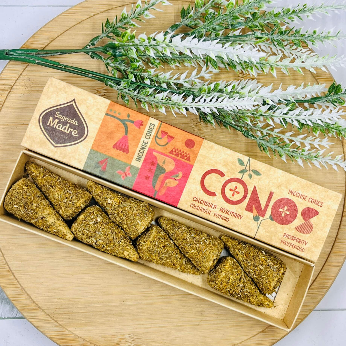 Handmade incense cones displayed in a wooden box with a label showing 'SAGRADA MADRE' and 'CONOS', accompanied by a sprig of rosemary.