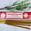 A packet of Satya Dragon's Blood incense sticks displayed alongside a sprig of dried herbs on a wooden surface.