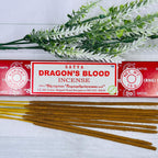 A packet of Satya Dragon's Blood incense sticks displayed alongside a sprig of dried herbs on a wooden surface.