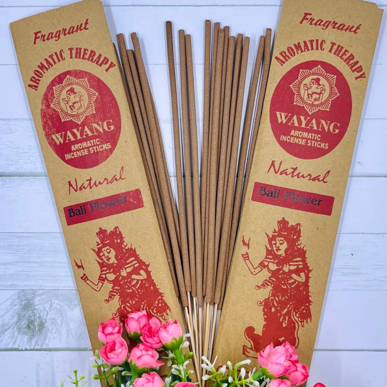 A packet of incense sticks branded 'WAYANG' with natural floral incense, displayed with pink flowers in the foreground.