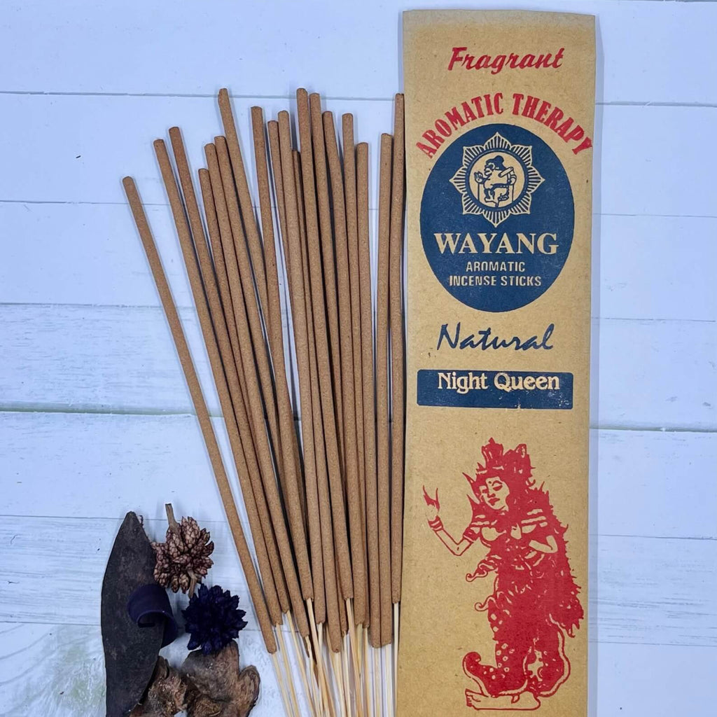 A packet of incense sticks labeled 'Night Queen' with a red graphic of a woman on the front, along with natural elements like herbs and flowers displayed around.