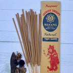A packet of incense sticks labeled 'Night Queen' with a red graphic of a woman on the front, along with natural elements like herbs and flowers displayed around.