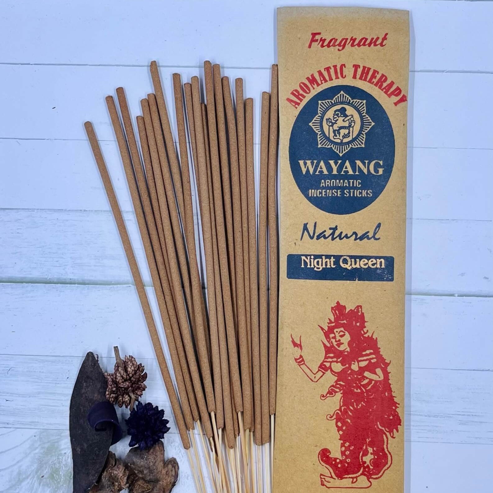 A packet of incense sticks labeled 'Night Queen' with a red graphic of a woman on the front, along with natural elements like herbs and flowers displayed around.