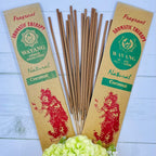 A packet of Balinese Coconut Incense with 20 sticks, displayed alongside a decorative flower arrangement. The packaging features a red traditional Bali figure illustration with 'Natural Coconut' written below.