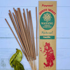 A packet of Balinese vanilla incense sticks displayed alongside some green leaves on a wooden surface.
