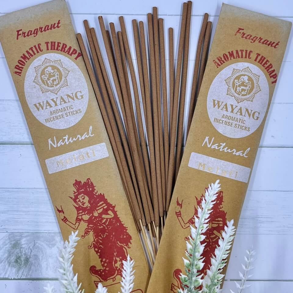 A packet of Balinese Melati incense sticks displayed alongside decorative foliage, with the brand 'Wayang' and the product name 'Melati' visible on the packaging.