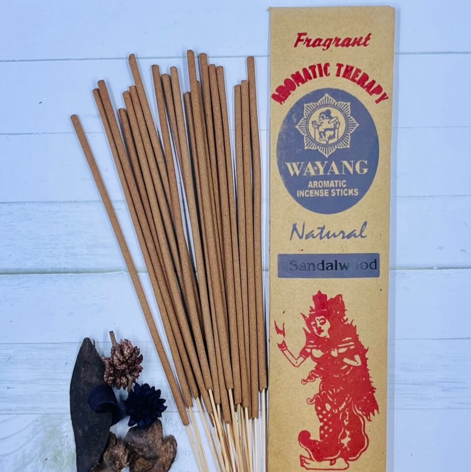 A packet of Balinese Sandalwood Incense with 20 sticks displayed in front of the packet. The incense sticks are beige, and there are decorative elements like dried flowers and leaves included.