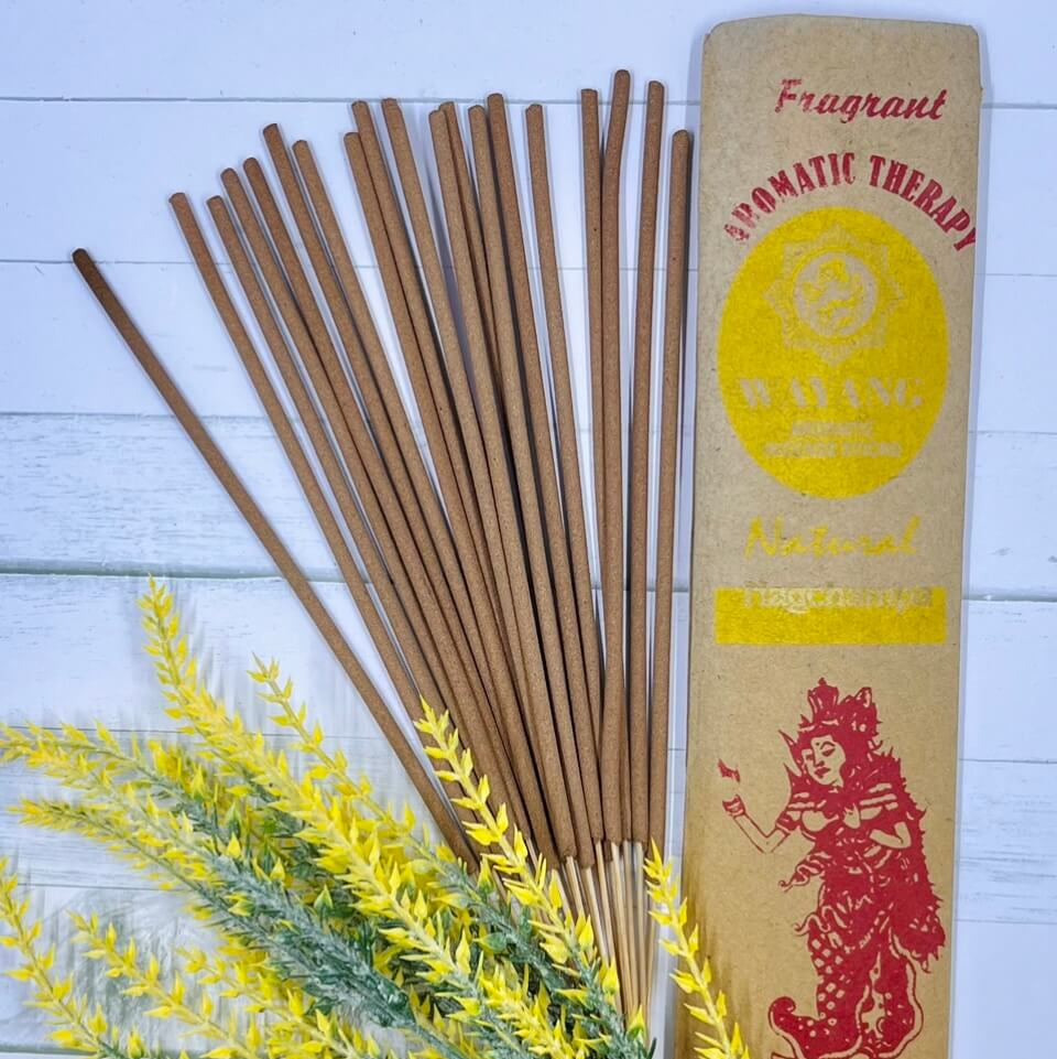 A packet of Balinese Nag Champa incense sticks displayed alongside a sprig of herbs.