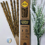 A box of Sagrada Madre natural incense sticks with citronella and orange, alongside decorative plants and a lit candle.