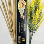 A packet of Banjara Aztec Incense PALO SANTO with several incense sticks displayed in front of it, against a white background with yellow flowers to the side.