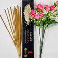 A packet of Banjara Aztec incense sticks with 'WILD ROSE' fragrance, displayed alongside a bouquet of pink roses. The packet is black with gold decorative elements.