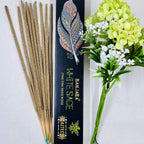 A packet of Banjara Aztec incense sticks labeled 'WHITE SAGE' displayed alongside a bundle of fresh flowers.