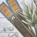 A pack of Auroshikha Natural Gum Copal Incense with 10 long dhoop sticks, displayed alongside decorative stones and herbs on a white wooden surface.