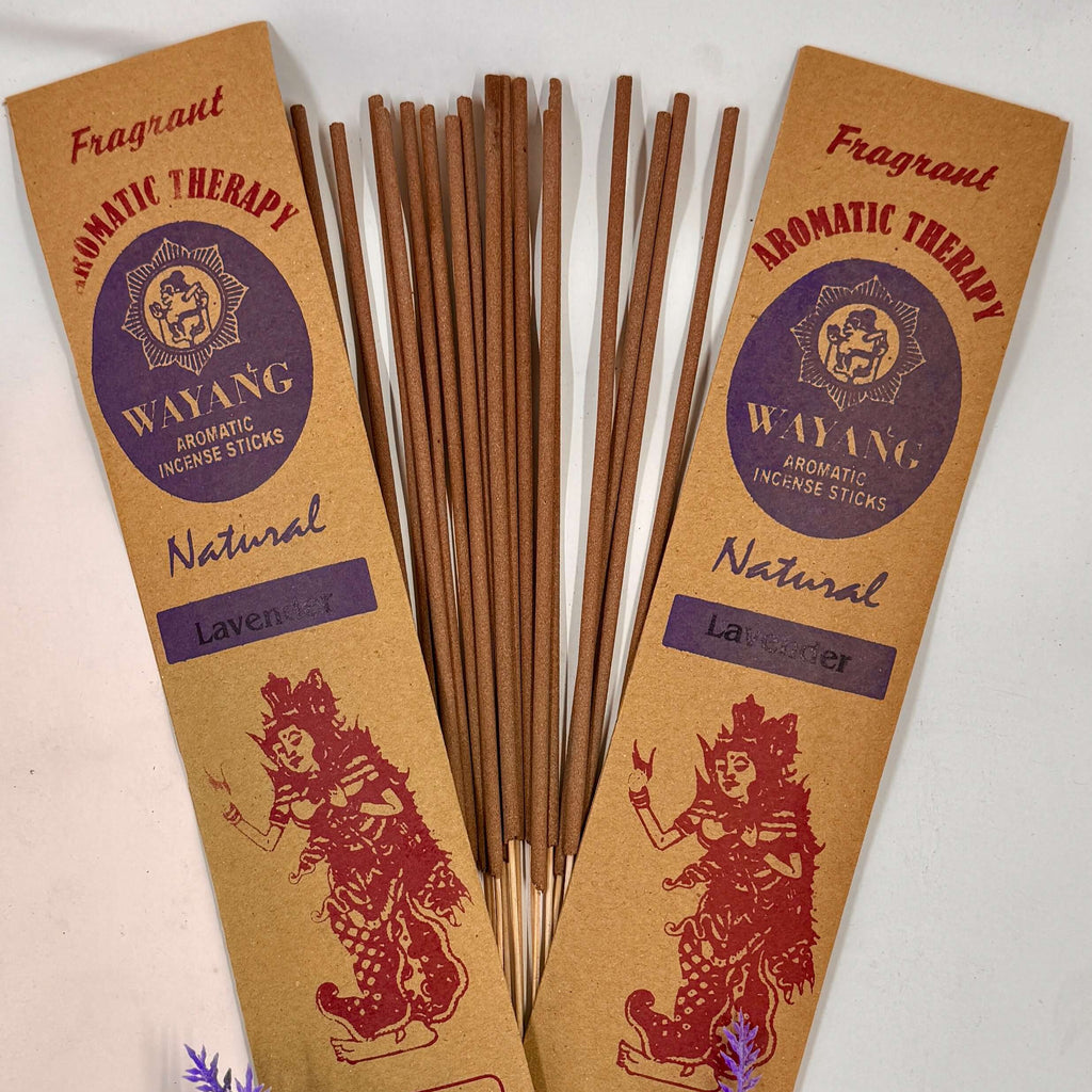 A packet of Wayang brand incense with 'Natural' labeled on it, displaying 20 sticks per packet, accompanied by purple flowers to the side.