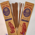 A packet of Wayang brand incense with 'Natural' labeled on it, displaying 20 sticks per packet, accompanied by purple flowers to the side.