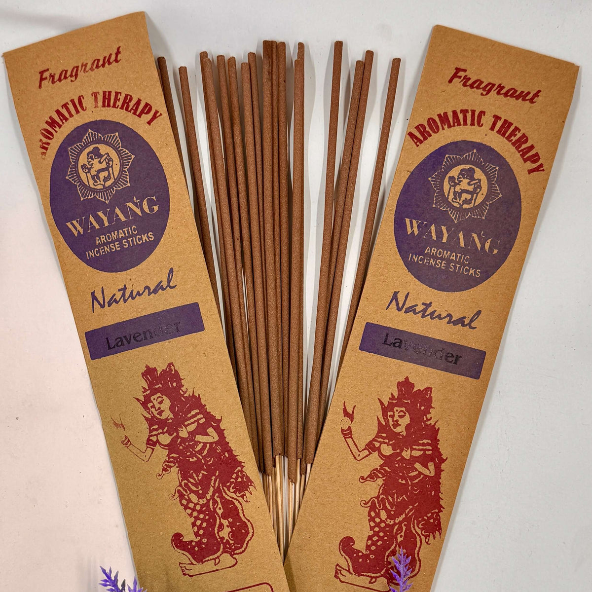 A packet of Wayang brand incense with 'Natural' labeled on it, displaying 20 sticks per packet, accompanied by purple flowers to the side.