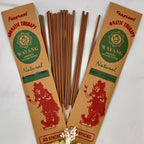 A bundle of brown incense sticks labeled 'Wayang', with packaging that includes the text 'Natural' and an illustration of a mouse. There are 20 sticks per packet, displayed with a decorative flower arrangement in the foreground.