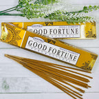 A pack of Deepika Good Fortune incense sticks displayed alongside decorative greenery against a white wooden background.