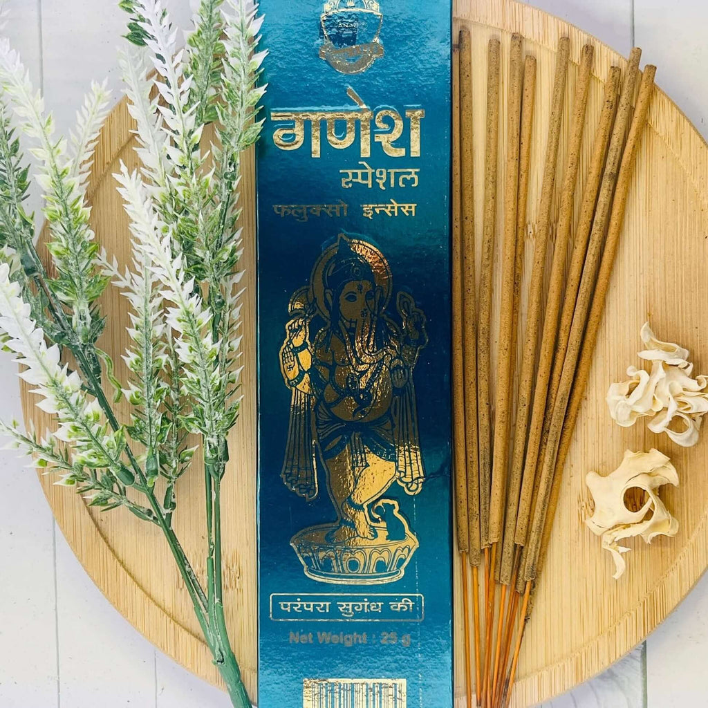 A packet of Anand Ganesh Fluxo incense displayed alongside a sprig of lavender and incense sticks on a wooden surface.