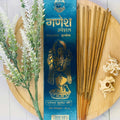 A packet of Anand Ganesh Fluxo incense displayed alongside a sprig of lavender and incense sticks on a wooden surface.
