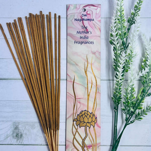 A pack of Mother's India Om Nag Champa incense sticks displayed alongside decorative floral elements on a wooden surface.
