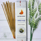 Incense sticks next to a box labeled 'Ayurvedic White Sage Masala Incense' with a illustration of a sage leaf and a honeycomb pattern.
