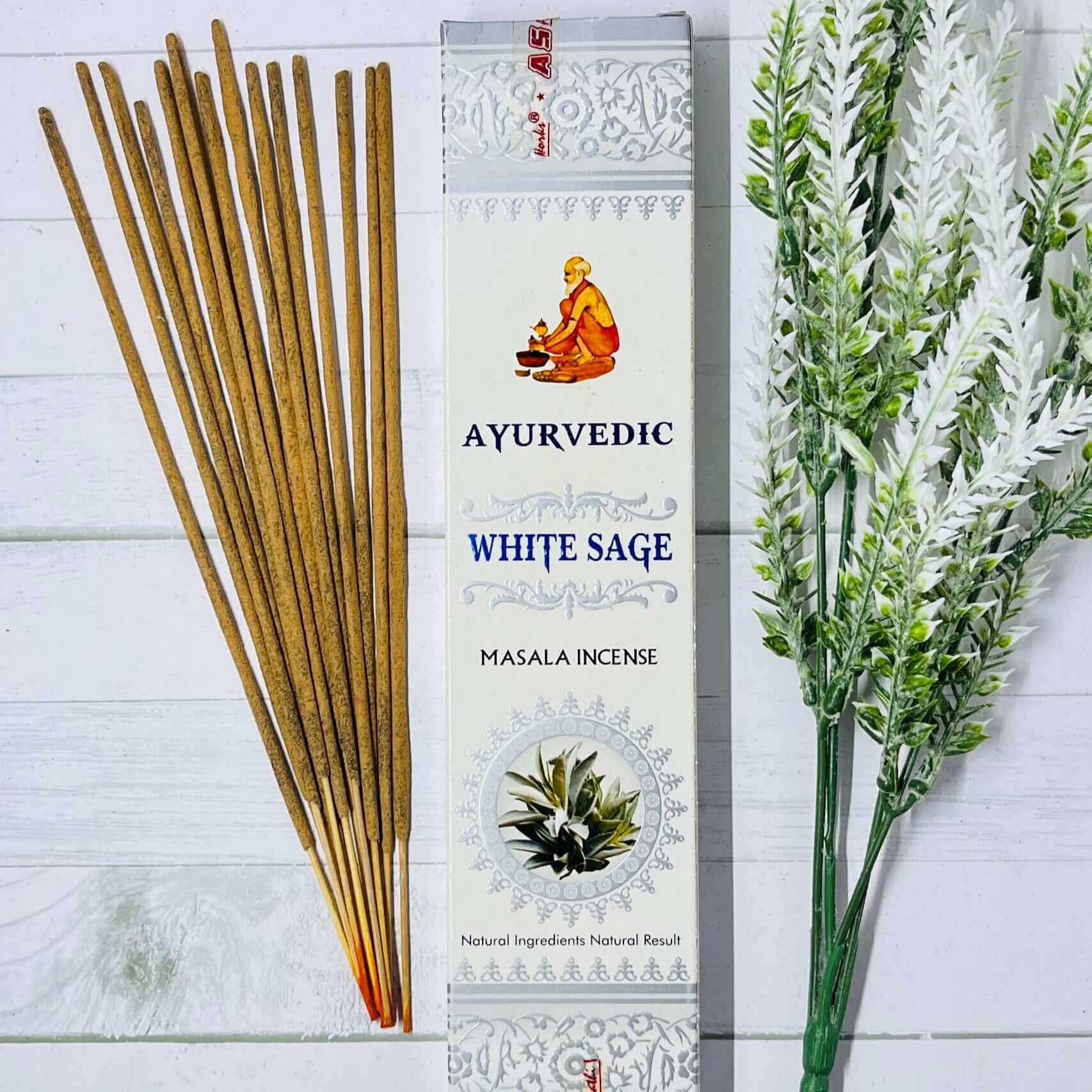 Incense sticks next to a box labeled 'Ayurvedic White Sage Masala Incense' with a illustration of a sage leaf and a honeycomb pattern.