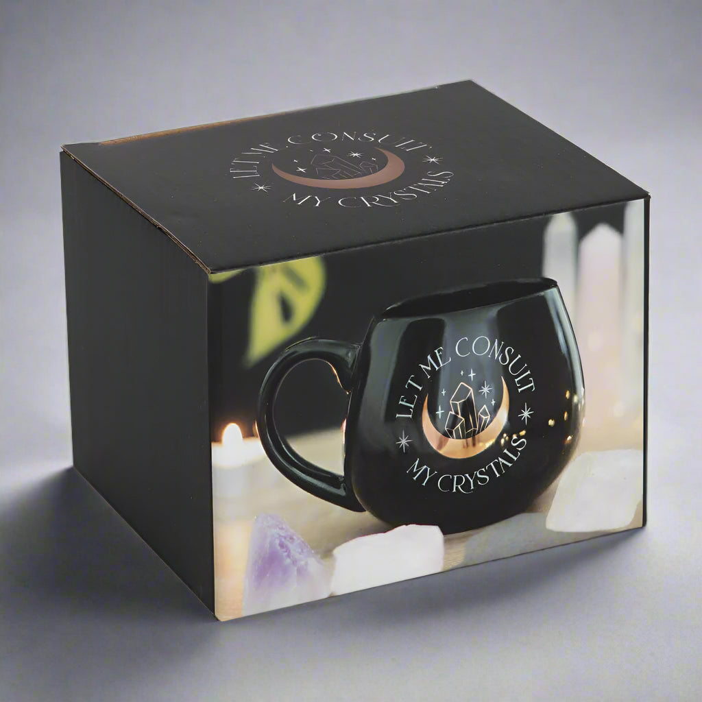 Black mug with 'Let Me Consult My Crystals' text in a decorative box