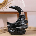 Black ceramic incense burner with smoke on a wooden surface