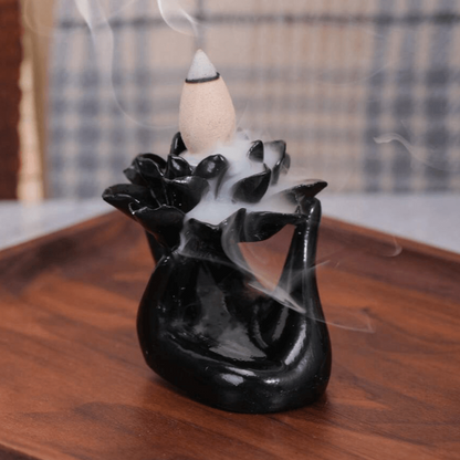 Black incense burner with smoke on a wooden surface