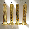 Four gold cylindrical objects with intricate patterns on a marble surface