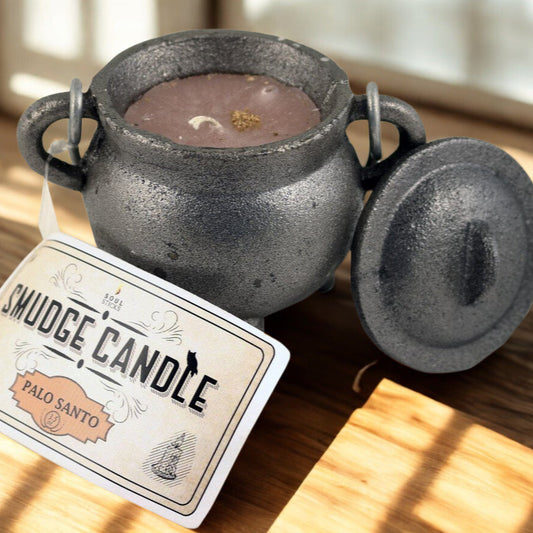 Smudge candle in a black pot with a label on a wooden surface