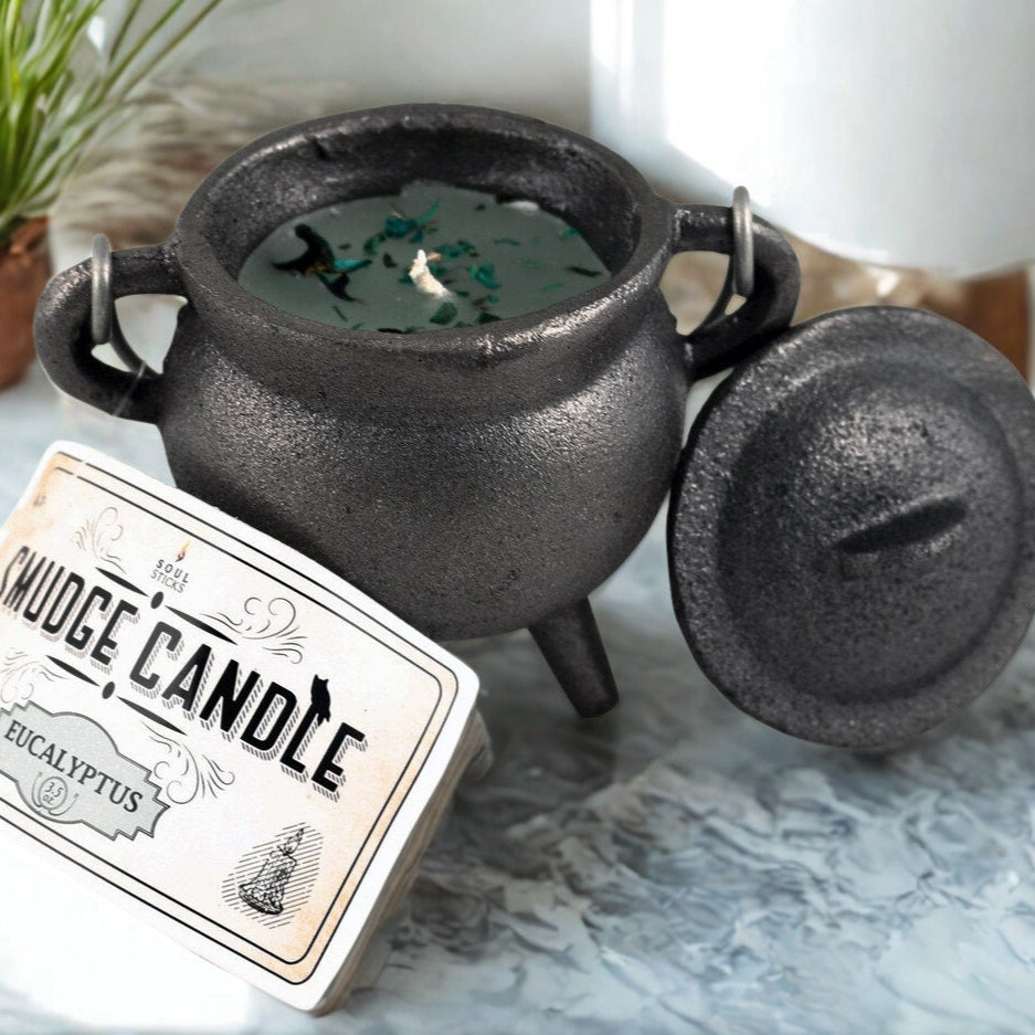 Black cauldron-shaped candle with a label on a marble surface