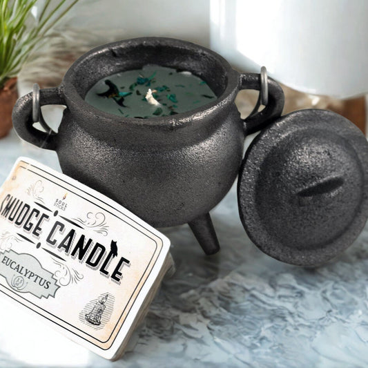 Black cauldron-shaped candle with a label on a marble surface
