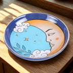 Ceramic plate with moon and cloud design on a wooden surface