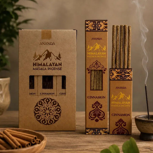 Ananda Himalayan Masala Incense in cinnamon scent, shown with its brown kraft paper packaging, a bundle of incense sticks, and a single incense stick burning in a small bowl on a wooden table.