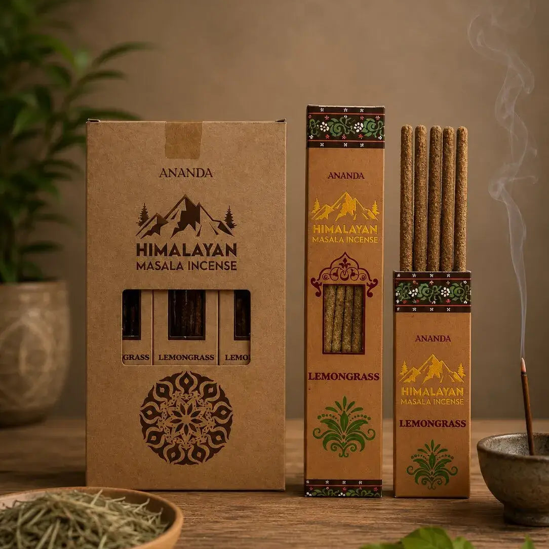 Three boxes of Ananda Himalayan Masala Incense on a wooden table, with one open box showing incense sticks, a bowl of dried herbs, and a smoking incense stick in a bowl, set against a warm neutral background.