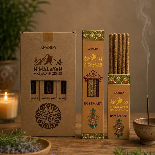 Three boxes of Ananda Himalayan Masala Incense on a rustic wooden table, surrounded by a lit candle, fresh rosemary, lavender, and a smoking incense stick in a bowl.
